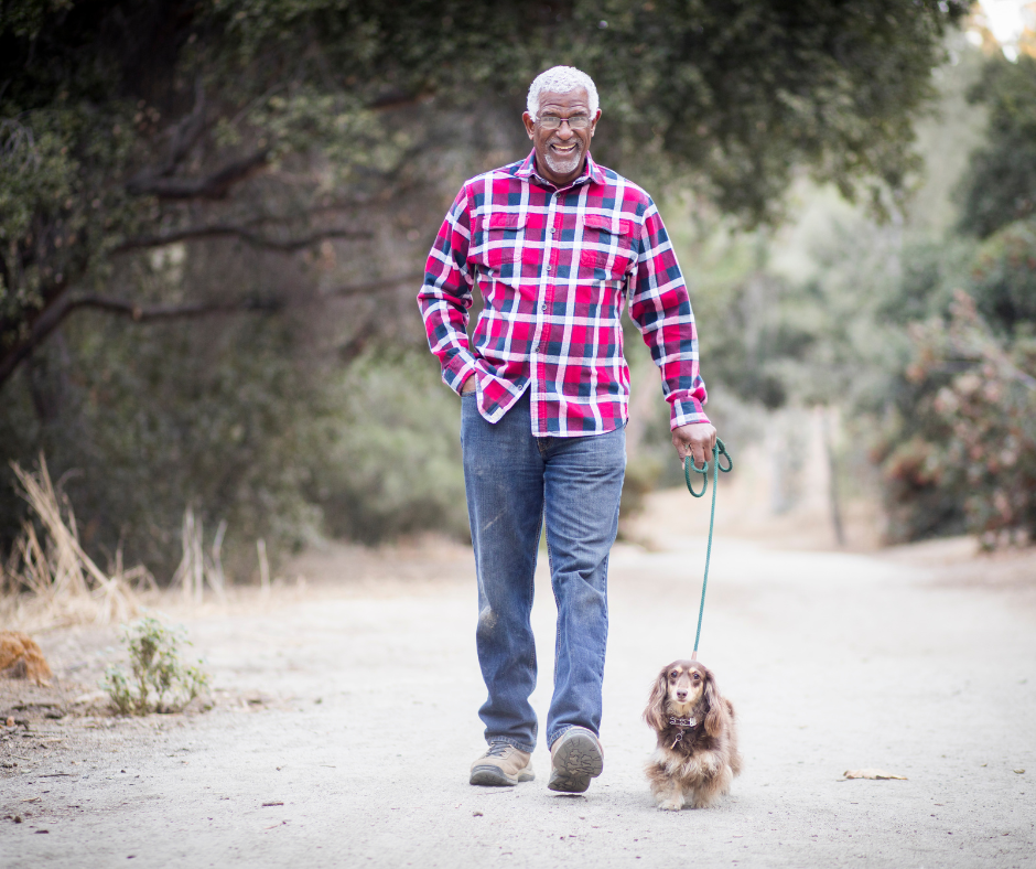 Medium shot of Elderly black man walking his dog