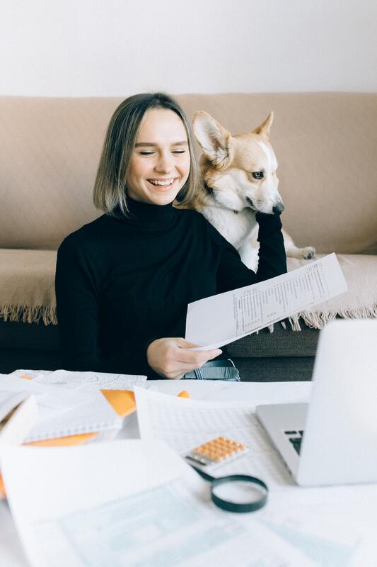 Woman petting dog while looking at paper