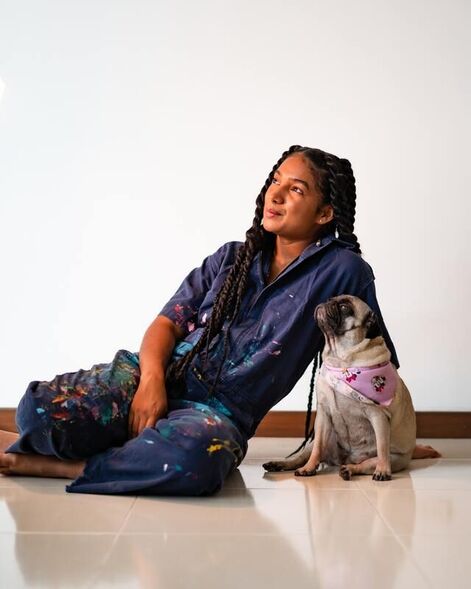 African American woman in paint-splattered overalls with pug